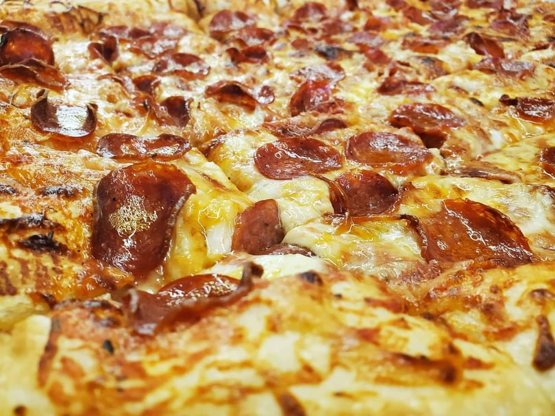 Close-up of a freshly baked pepperoni pizza, glistening with melted cheese and crispy edges.